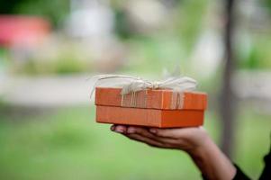 Hand and orange gift boxes give to your loved ones. Gift ideas photo