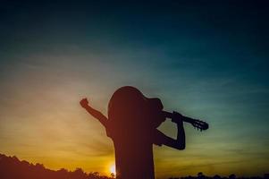 silueta de un guitarrista en las sombras a la luz del atardecer, concepto de silueta. foto