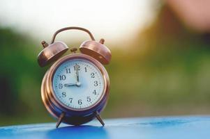 imagen de reloj de alarma dorada colocada en una mesa azul, concepto puntual de fondo verde con espacio de copia foto