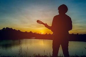 Silhouette of a guitarist in the shadows at sunset light, silhouette concept. photo