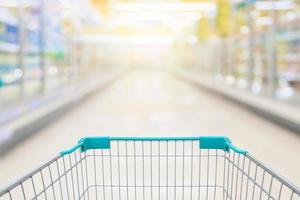 Shopping cart view with milk and yogurt product shelves aisle in supermarket