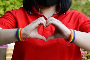 Rainbow wristbands in wrists of asian boy couple with blurred background, concept for celebration of lgbt community in pride month or in June around the world photo