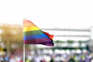 bandera del arco iris, símbolo de la comunidad lgbt, ondeando en el viento con un fondo azul cielo nublado. foto