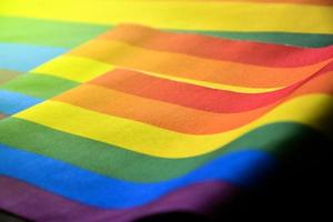 bandera del arco iris, un símbolo para la comunidad lgbt, ondeando en el viento con estudiantes asiáticos borrosos en el fondo de las actividades matutinas. concepto para apoyar y hacer campaña a las comunidades lgbt en la escuela foto