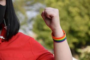 Rainbow wristbands in wrists of asian boy couple with blurred background, concept for celebration of lgbt community in pride month or in June around the world photo