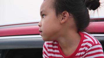 linda niña asiática sonriendo y divirtiéndose para viajar en auto y mirando por la ventana del auto. familia feliz disfrutando de un viaje por carretera en vacaciones de verano.
