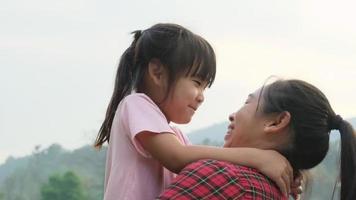 la pequeña hija feliz abraza y besa a su madre en el parque. concepto de relación familiar video