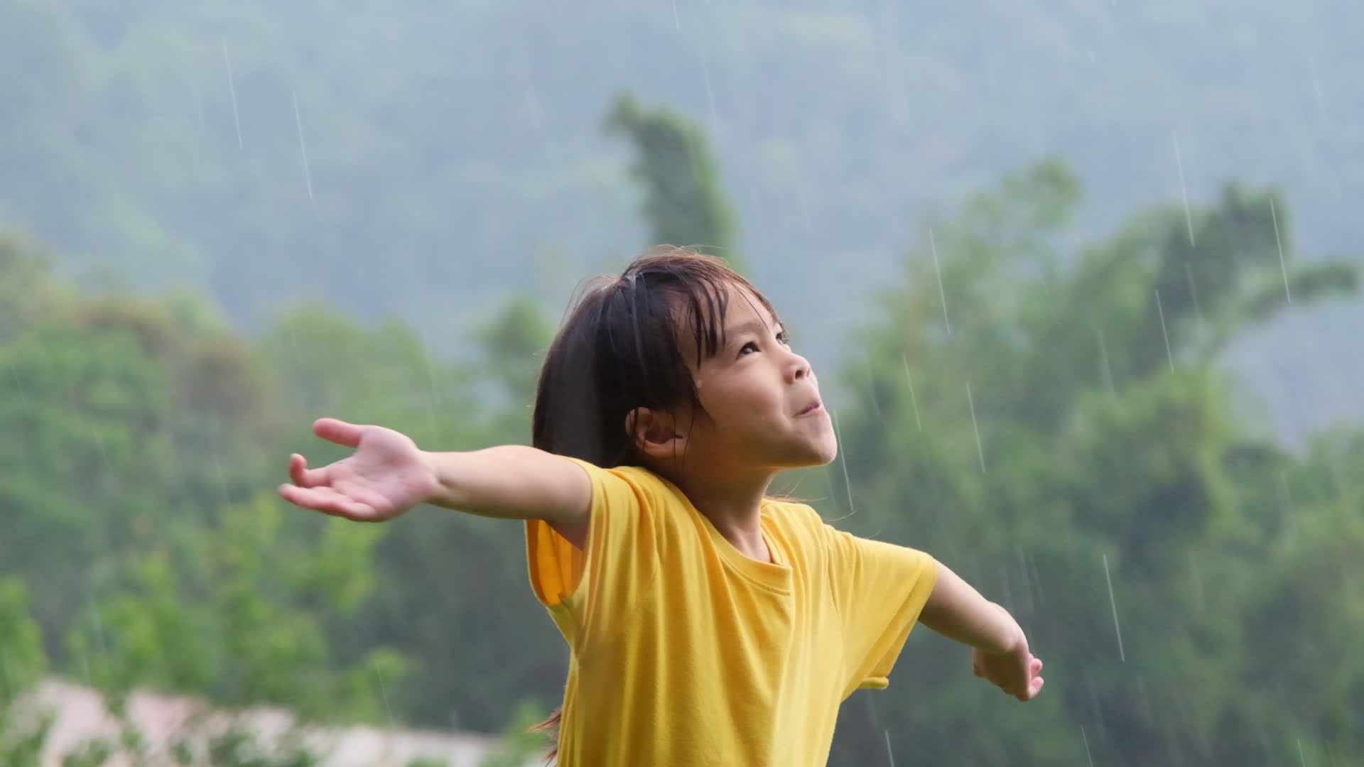 Cute little girl having fun catching rain drops. Kids play in summer