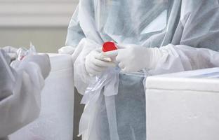 Focus at health worker's hand is collecting sputum and saliva samples to detect covid-19 infectious patients in public area photo