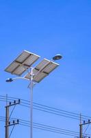 Low angle view of streetlight post and solar power panel with electric poles against blue clear sky in vertical frame