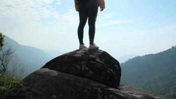 Female hiker standing on rocks on the background of sunrise between mountains. Successful female hikers enjoy nature on the top of the mountain. video