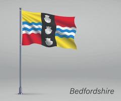 Waving flag of Bedfordshire - county of England on flagpole. vector