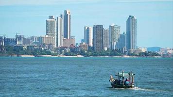 Fishing boat drive on the sea and condominium building hotel in pattaya city background