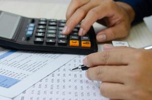 mano de hombre sosteniendo un bolígrafo y una calculadora haciendo planes financieros impuestos e inversión empresarial. foto