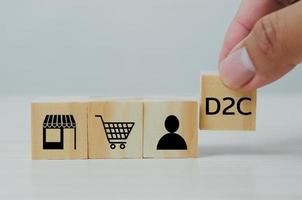 Hand put wooden cubes with Direct to Consumer D2C on table and copy space.Business concepts. photo