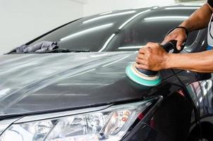 hombre que trabaja para pulir, recubrir autos. El pulido del automóvil ayudará a eliminar los contaminantes en la superficie del automóvil. El encerado de la superficie del automóvil hará que brille después de pulir el automóvil. foto