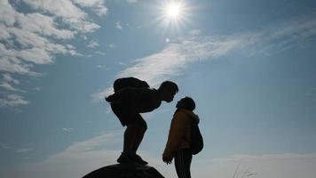 silhouet van verliefde paar zoenen op de top van de berg. liefde en reisconcept. video