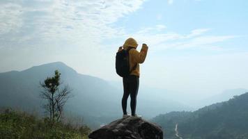 erfolgreiche weibliche wanderer öffnen die arme oben auf dem berg. glückliche Frau, die mit erhobenen Händen auf dem Hintergrund des Sonnenaufgangs zwischen den Bergen steht video