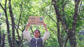 retrato de mujer de pie con el cartel de amor a tu madre tierra en el parque de verano. Mujeres activistas voluntarias demuestran la protección del medio ambiente. día Mundial del Medio Ambiente video