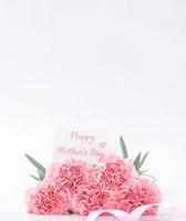 Top view of elegance blooming sweet pink color tender carnations isolated on bright white background with card, may mothers day mum greeting design concept, close up, copy space photo