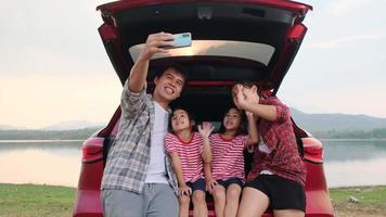 familia feliz disfrutando de un viaje por carretera en vacaciones de verano. la familia viaja por la carretera en su coche favorito. concepto familiar de vacaciones y viajes. video