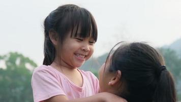gelukkig dochtertje knuffelt en kust haar moeder in het park. familie relatie concept video