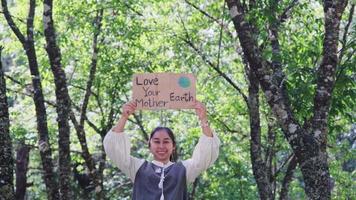 retrato de mujer de pie con el cartel de amor a tu madre tierra en el parque de verano. Mujeres activistas voluntarias demuestran la protección del medio ambiente. día Mundial del Medio Ambiente video