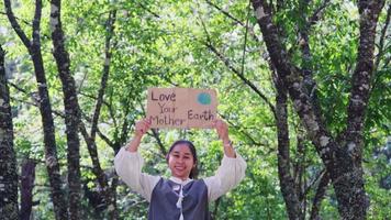 Portrait of woman standing with Love Your Mother Earth poster at the summer park. Female volunteer activists demonstrate protecting the environment. World Environment Day video