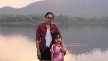 madre feliz con niños disfrutando de la naturaleza sonriendo y mirando la cámara junto al lago en vacaciones de verano. concepto familiar de vacaciones y viajes. video