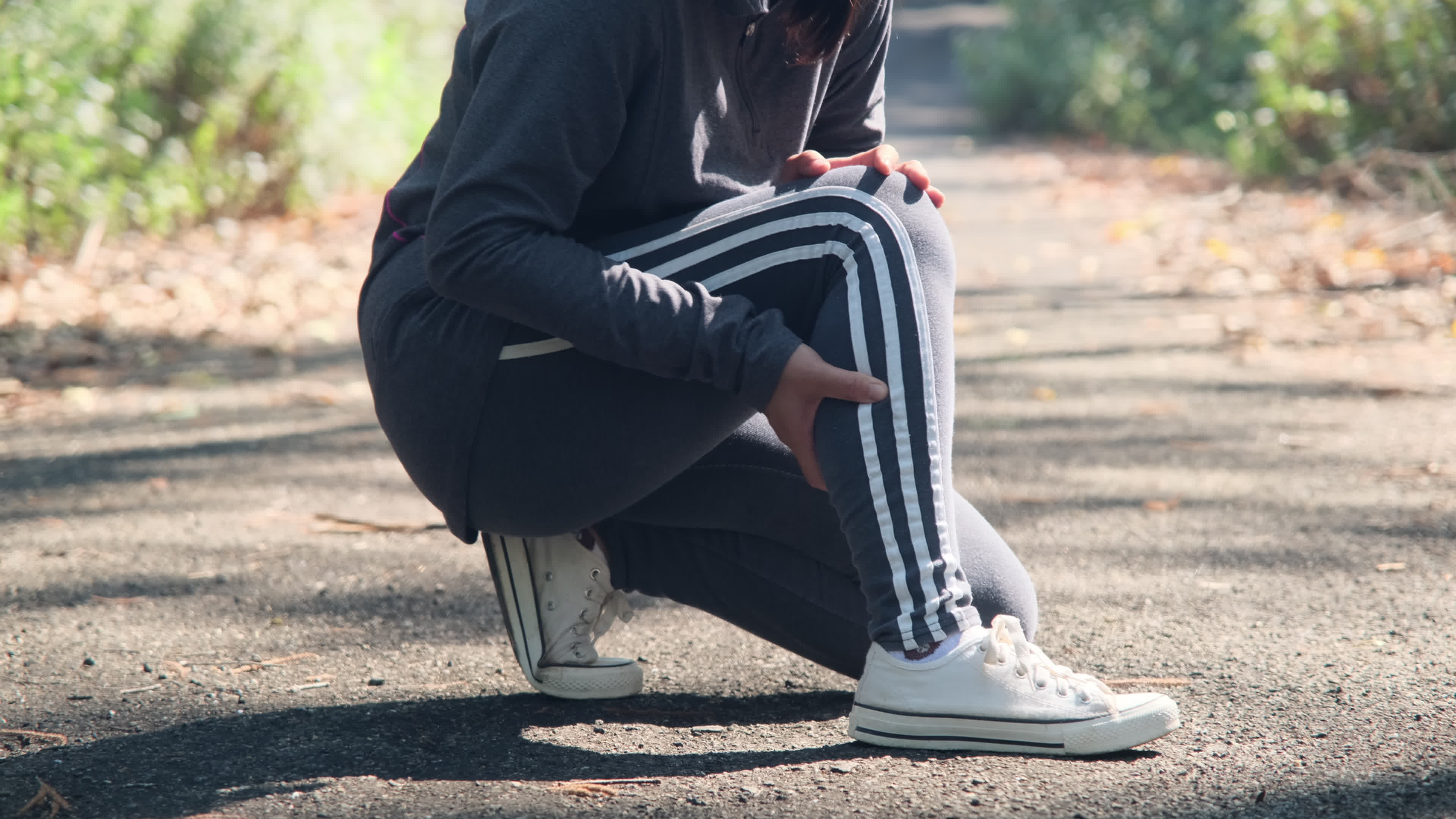 Female athlete holds calf muscle injury after cramping while training