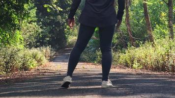 mujer asiática deportiva estira las piernas antes de trotar en un parque de verano. concepto de fitness y estilo de vida. video