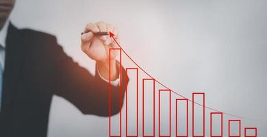 Business write growth graph losses on the stock market chart concept, Business use pen touch line market chart and Red arrows fall to the ground, indicating the economic recession. photo