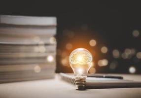 Thinking and creative concept, Light bulb on the Book and light bulb style bokeh vintage dark background,Concept The idea of reading books, knowledge, and searching for new ideas. photo