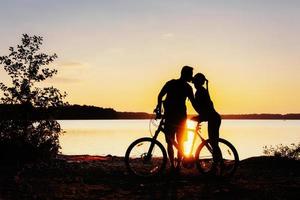 couple on a bicycle at sunset by the lake photo