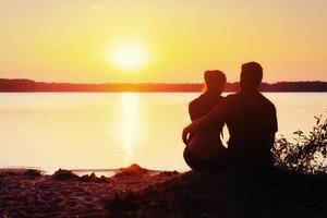 pareja romántica en la playa en el colorido fondo de la puesta de sol foto