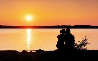 pareja romántica en la playa en el colorido fondo de la puesta de sol foto