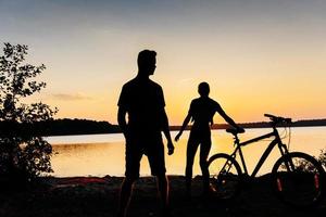 pareja en bicicleta al atardecer junto al lago foto