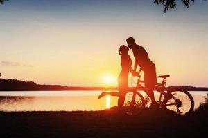 pareja en bicicleta al atardecer junto al lago foto