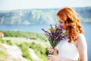 bride with a bouquet of flowers near the water photo