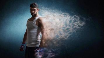 Muscular male boxer standing over dark background particles effect. photo