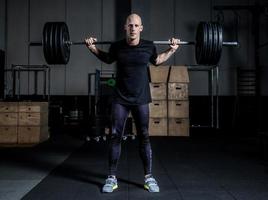 Athletic Muscular Man Holding Barbell On Your Shoulders In Gym. Dramatic Color Grading. photo