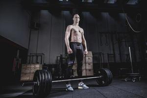 Muscular man Standing at Barbells Before Exercise. Dramatic Color Grading. photo