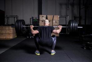 Athletic Muscular Man Lifting Weights and Doing Back Squat in Gym. Dramatic Color Grading. photo