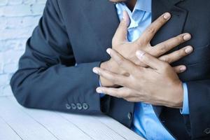 young man suffering pain in heart and holding chest with hand photo