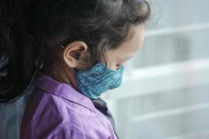 a upset child girl with face mask looking down photo