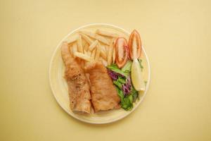 Fish fillet, lemon , chips and potato mash on table photo