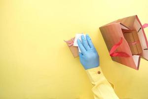 hand in latex gloves wapping a gift box with tissue photo