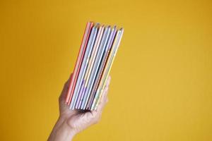 hand holding stack of books on color background photo