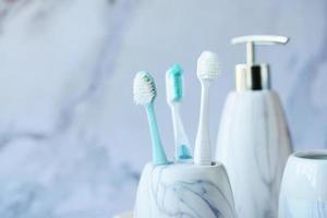 Cepillos de dientes en taza blanca y jabón sobre fondo de azulejos foto