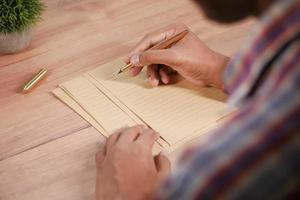 rear view of young man writing with a fountain pen on a vintage paper photo